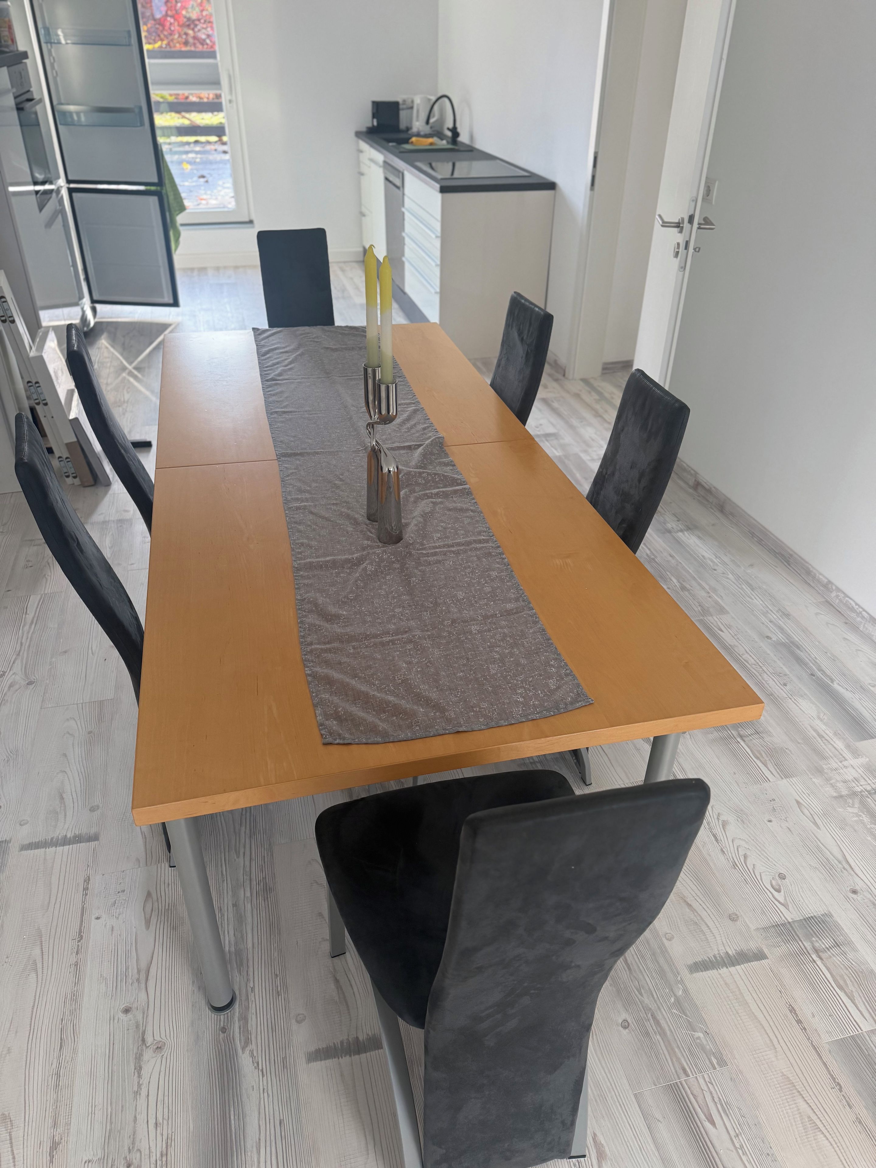 Una mesa de comedor con sillas, una zona de cocina y vistas al exterior.