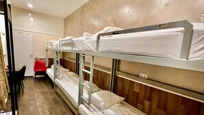 Una camera con letto a castello, pavimento in legno, una scrivania con sedia e una poltrona rossa.