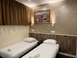 A hotel room with two single beds, a painting of a cityscape, and a wooden headboard. - Dam Hotel (Amsterdam)