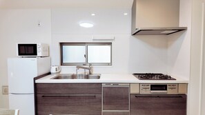 Cocina compacta equipada con microondas, hervidor, pileta, estufa y lavavajillas.