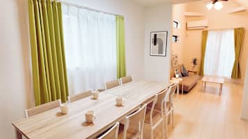A dining area with a wooden table and chairs, a sofa, and a small table with a plant.