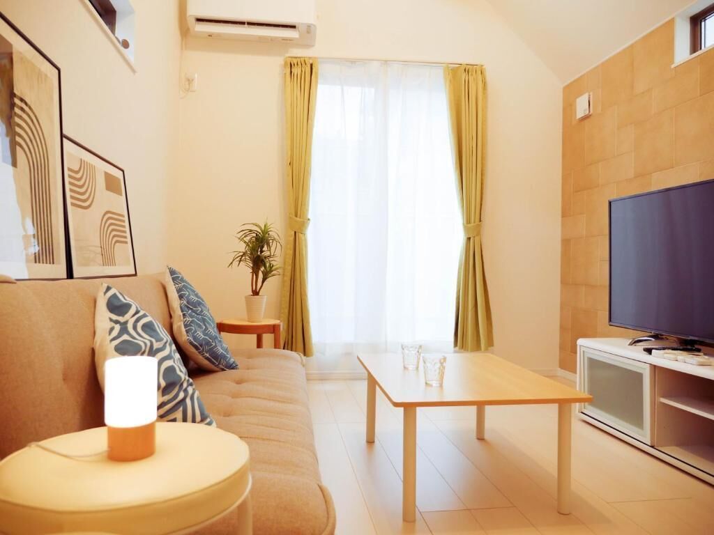 Un salon avec un canapé, une table basse, un téléviseur et une fenêtre avec des rideaux.