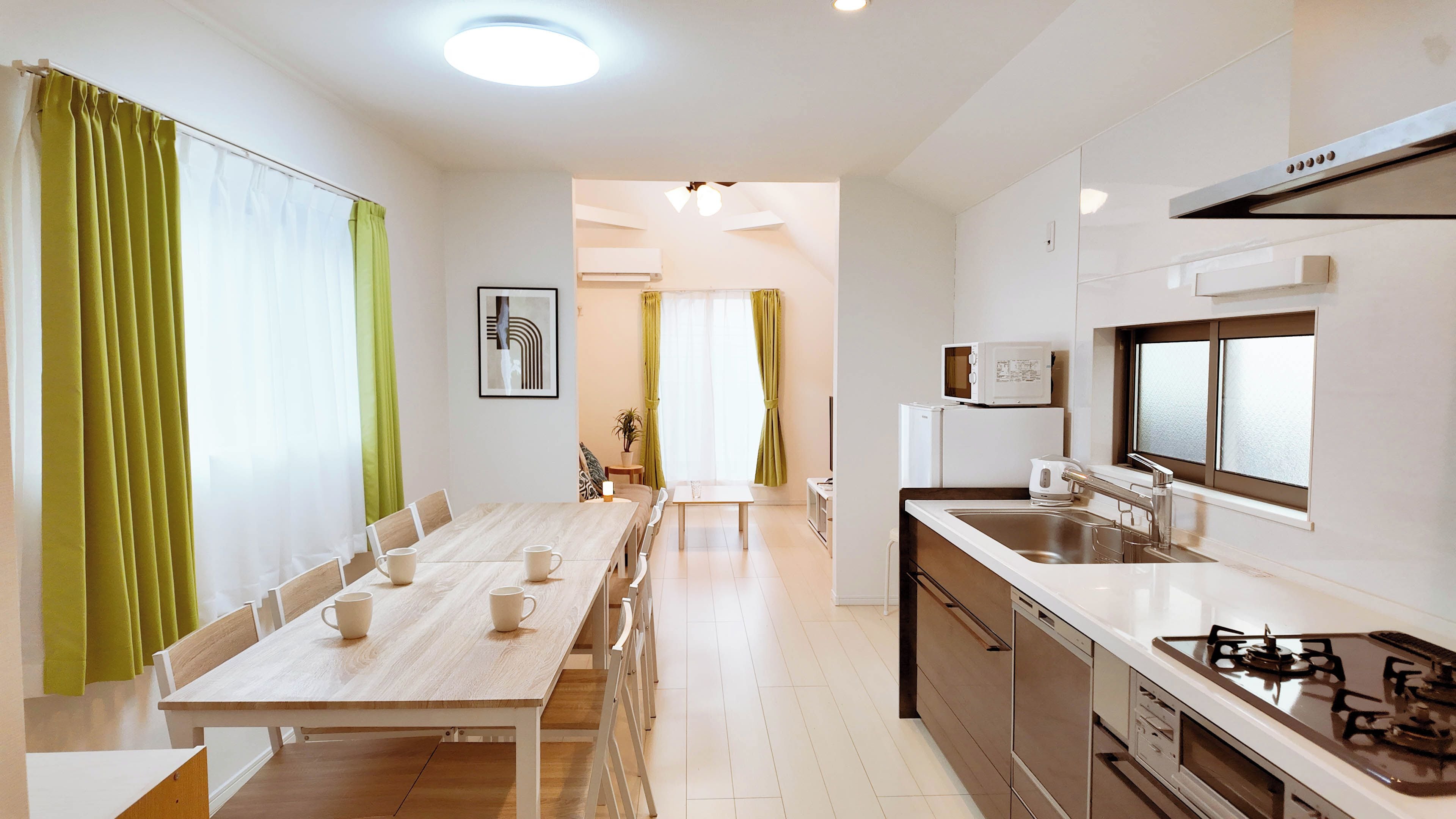 A modern kitchen with a gas stove, a sink, and a dining area with a table and chairs.