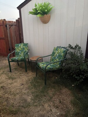 A patio area with two green metal chairs, a small round table, and a hanging plant. - Welcome to Oakdale, Ca Comfortable Private Bedroom/Bath,
69 miles to Yosemite. (Oakdale)