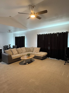 A living room with a sectional sofa, a coffee table, a ceiling fan, and black curtains. - Charming Pet friendly 3-bedroom house with AC in Milliken (Milliken)