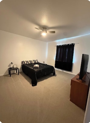 A bedroom with a bed, a ceiling fan, a TV, and a window with curtains. - Charming Pet friendly 3-bedroom house with AC in Milliken (Milliken)