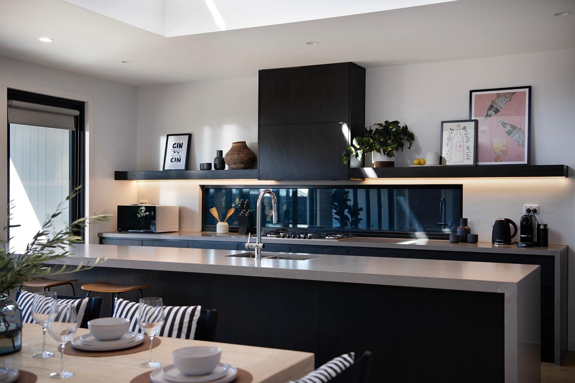 A modern kitchen with a central island, built-in appliances, and a dining area with striped chairs.