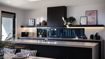 A modern kitchen with a central island, built-in appliances, and a dining area with striped chairs.