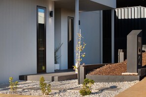 Een modern gebouw met een minimalistisch ontwerp, een plat dak, grote ramen en een goed onderhouden tuin met grind en kleine planten.