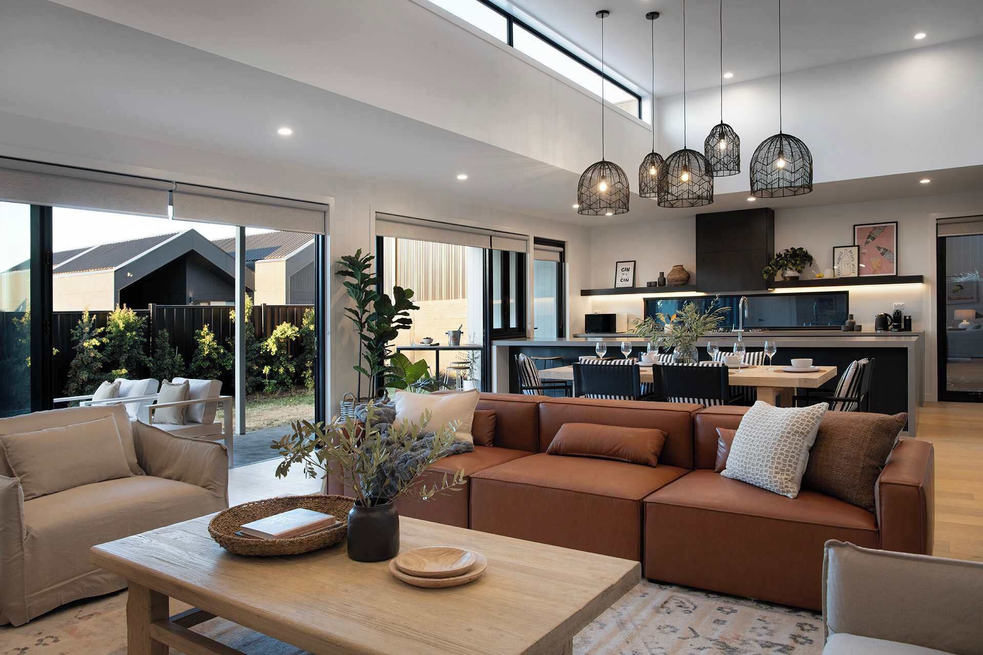 A modern living room with a sofa, a coffee table, and a dining area with chairs and a table.