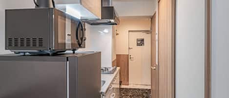 Una cocina compacta con microondas integrado, estufa y campana extractora.