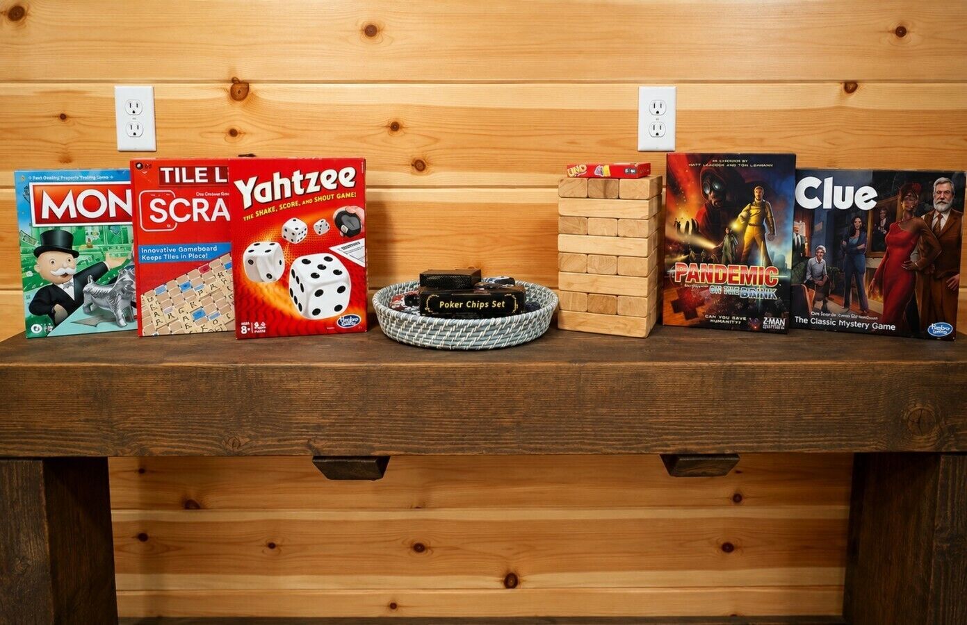 Un estante de madera con varios juegos de mesa, incluyendo Monopoly, Tile L SCRA, Yahtzee, UNO y Clue.