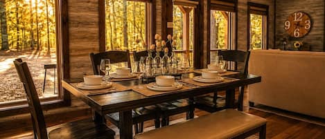 A dining area with a wooden table set for four, surrounded by chairs, with a bench at the end.