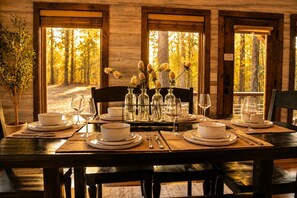 Une table à manger dressée pour quatre personnes, avec de l’assiette, des bols et des verres blancs, et des chaises disposées de chaque côté.