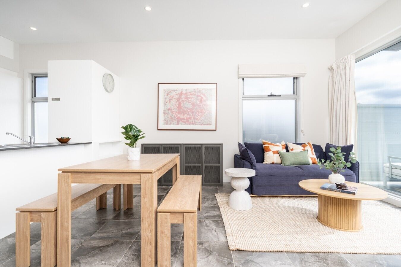 A modern living room with a sofa, coffee table, and dining area.