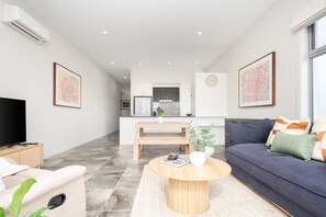 A modern living room with a sofa, a coffee table, and a TV. - Quiet Turner Stay | Walk to Braddon & ANU (Turner)
