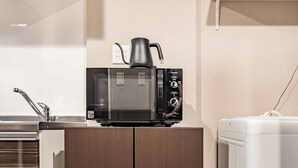 A compact kitchenette with a microwave, kettle, and a small refrigerator. - Apartment Hotel 11 Kuromon 8 (Osaka-shi)