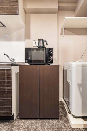 A compact kitchenette with a microwave, kettle, and a small refrigerator. - Apartment Hotel 11 Kuromon 8 (Osaka-shi)