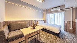 A modern hotel room with a sofa, a small table, a bed, and a window with curtains. - Apartment Hotel 11 Kuromon 8 (Osaka-shi)