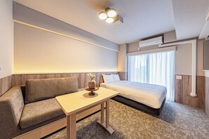 A modern hotel room with a sofa, a small table, a bed, and a window with curtains. - Apartment Hotel 11 Kuromon 8 (Osaka-shi)