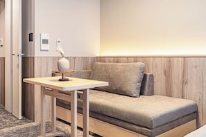 A modern hotel room with a wooden wall panel, a sofa, a small table with a vase, and a door with a handle. - Apartment Hotel 11 Kuromon 8 (Osaka-shi)