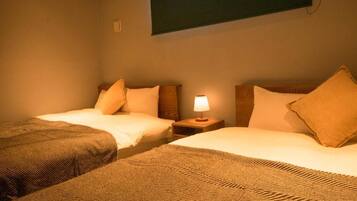 Een hotelkamer met twee enkele bedden, een nachtkastje met een lamp en een aan de muur bevestigde televisie.