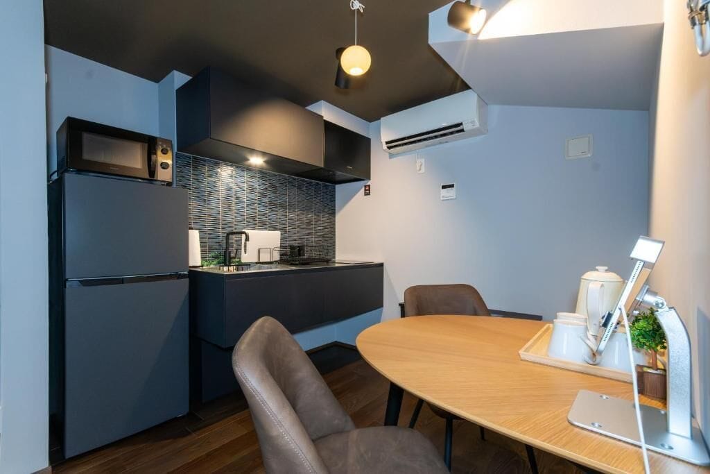 A modern kitchen with a built-in microwave, refrigerator, and a small dining area with a table and chairs.