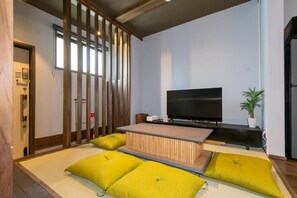 Ein modernes Wohnzimmer mit Flachbildfernseher, einem niedrigen Couchtisch und gelben Kissen.