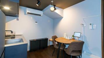 Una cocina compacta con lavamanos, un refrigerador pequeño y un comedor con mesa y sillas.