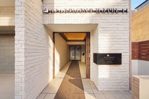 Ein moderner Hotelzugang mit einem Schild, das 'APARTMENT HOTEL 11' anzeigt, und einer Adressschild mit der Aufschrift 'Kuromon 9'.