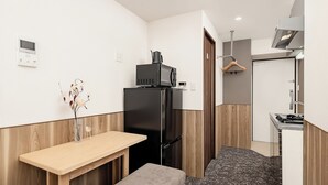 A compact kitchenette with a black refrigerator, a microwave, and a small countertop. - Apartment Hotel 11 Kuromon 9 (Osaka-shi)
