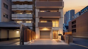 A modern multi-story building with a unique architectural design, featuring a curved facade and multiple balconies. - Apartment Hotel 11 Kuromon 9 (Osaka-shi)