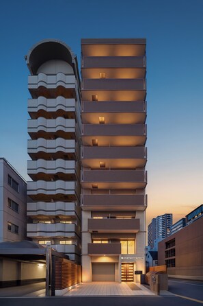 En modern byggnad med flera våningar och en unik arkitektonisk design, med en böjd fasad och flera balkonger.