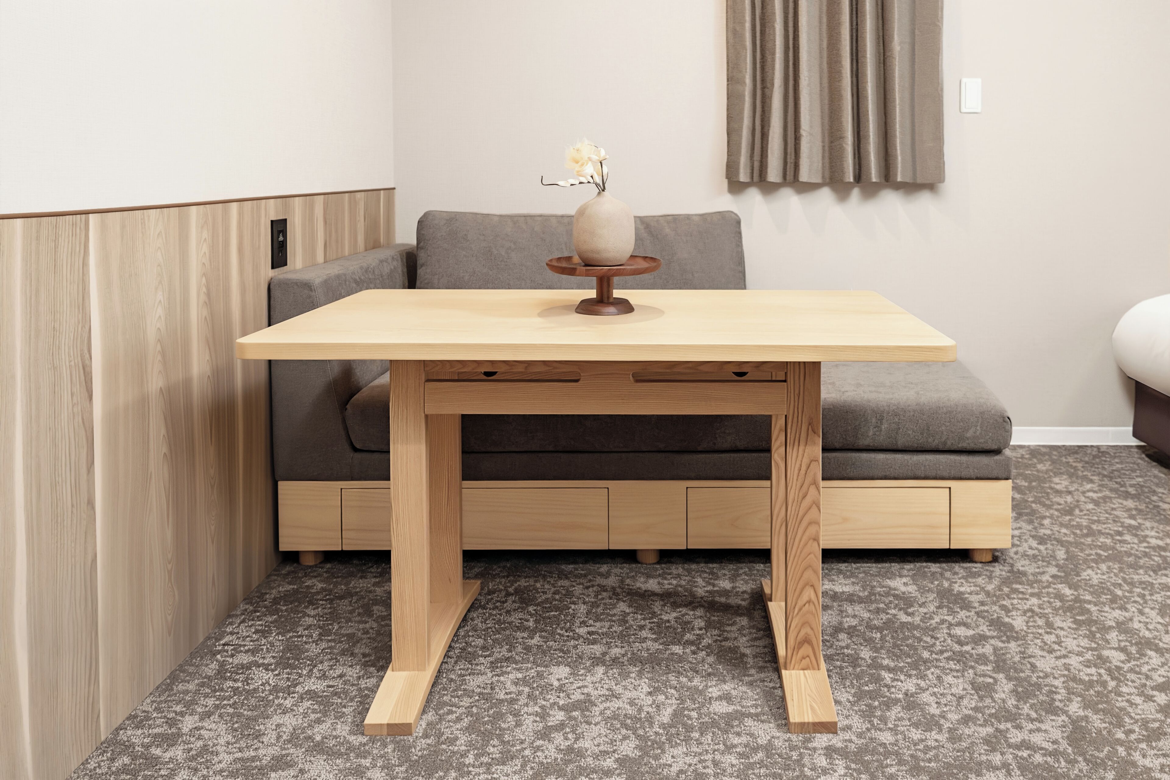 Una habitación pequeña y moderna con una mesa de madera, sofá gris y alfombra gris.