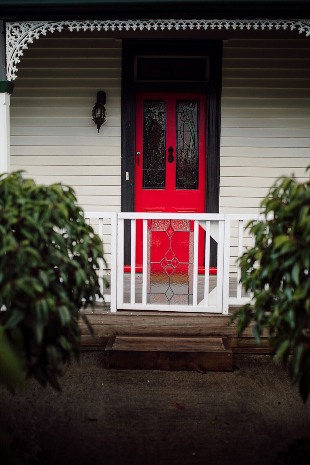 Charming porch entry with a striking red stained-glass front door