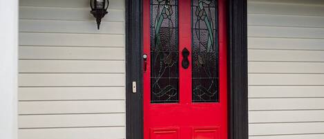 A house with a red door, white porch railing, and a small porch area.