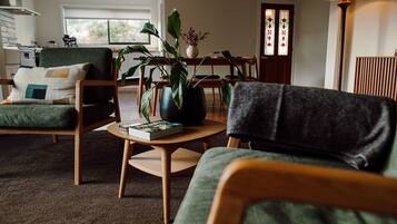 A cozy living room with a sofa, a coffee table with a book, and a potted plant.