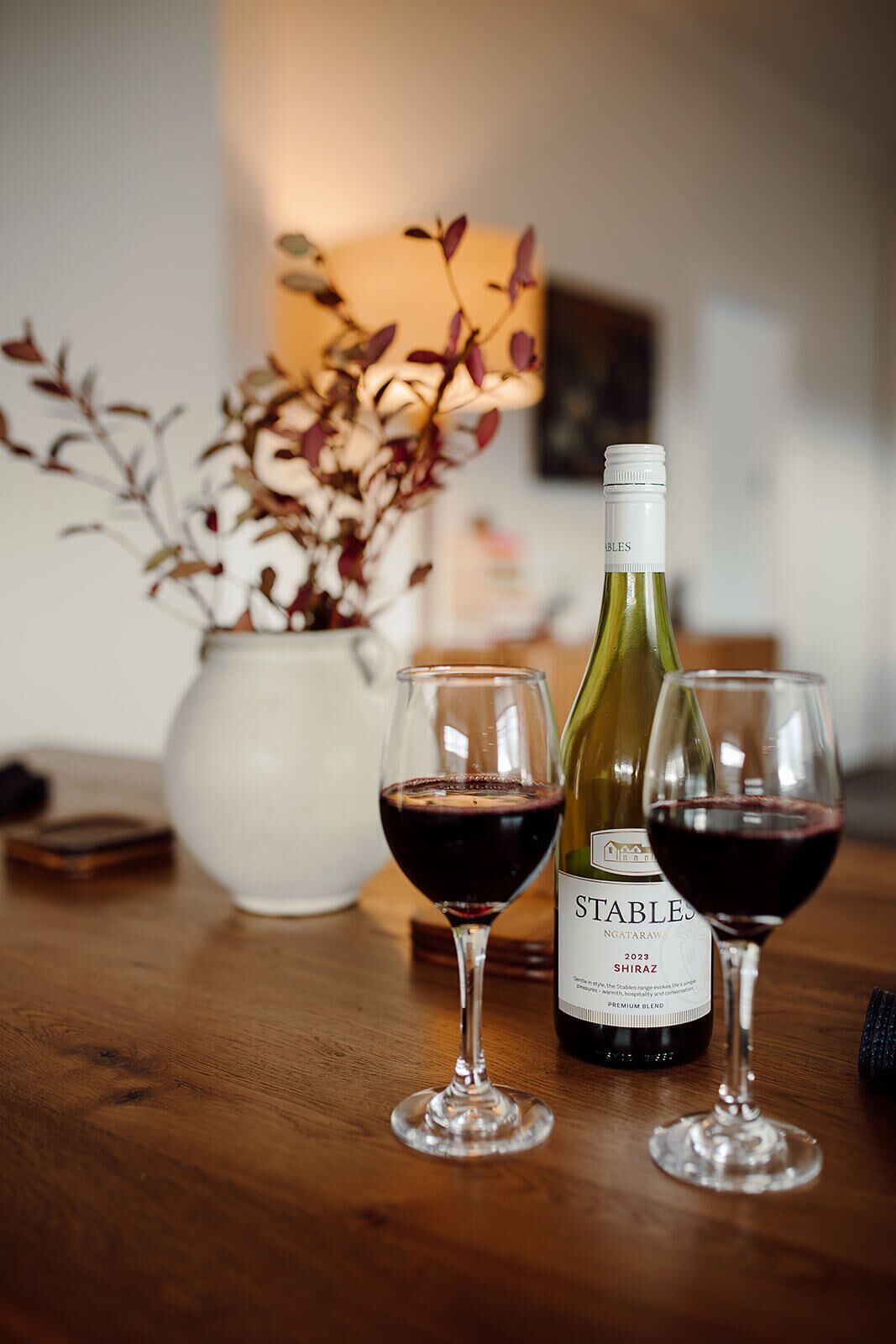 A bottle of wine and two glasses on a wooden table.