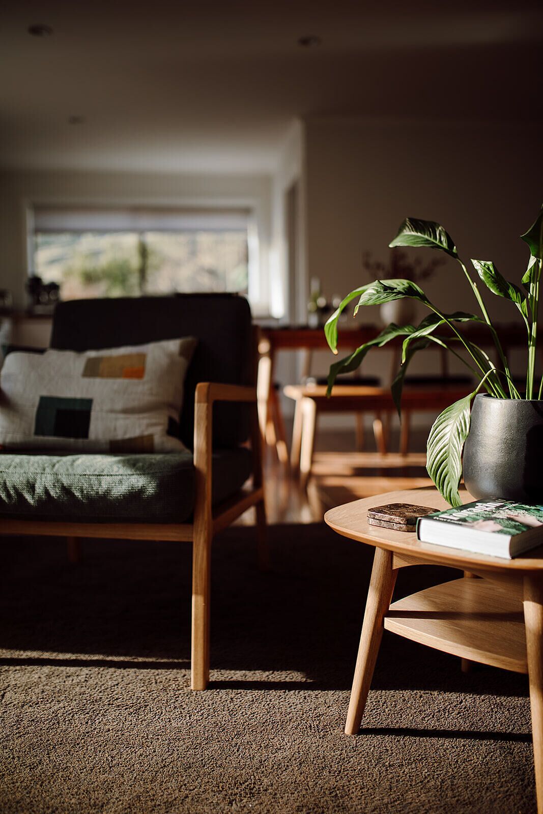 A cozy living room with a sofa, a coffee table with a book, and a potted plant.