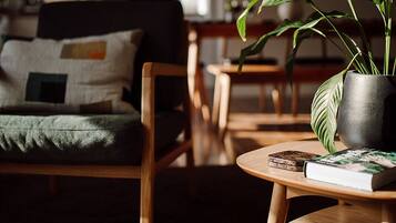 A cozy living room with a sofa, a coffee table with a book, and a potted plant.