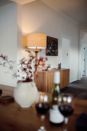 Un soggiorno moderno con una scrivania di legno per la reception, una lampada, un vaso con fiori e un quadro appeso al muro.