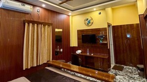 A hotel room with a bed, a ceiling fan, a TV, a mirror, and a wardrobe. - MH Club And Resorts (Nagri)
