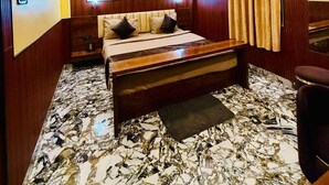 A bedroom with a bed, a ceiling fan, a wall-mounted air conditioner, and a patterned carpet. - MH Club And Resorts (Nagri)