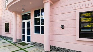 A pink building with a covered entrance, a window with a view, and a light fixture. - MH Club And Resorts (Nagri)