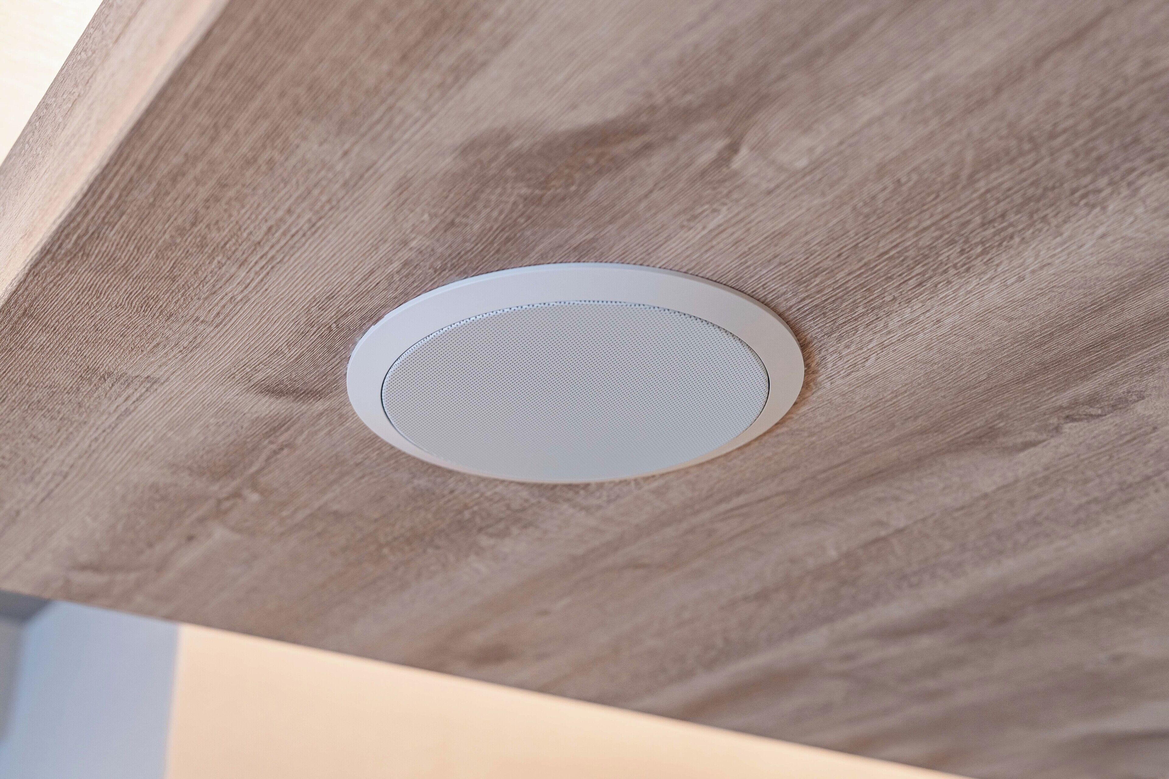 A ceiling with a circular vent and a textured surface.