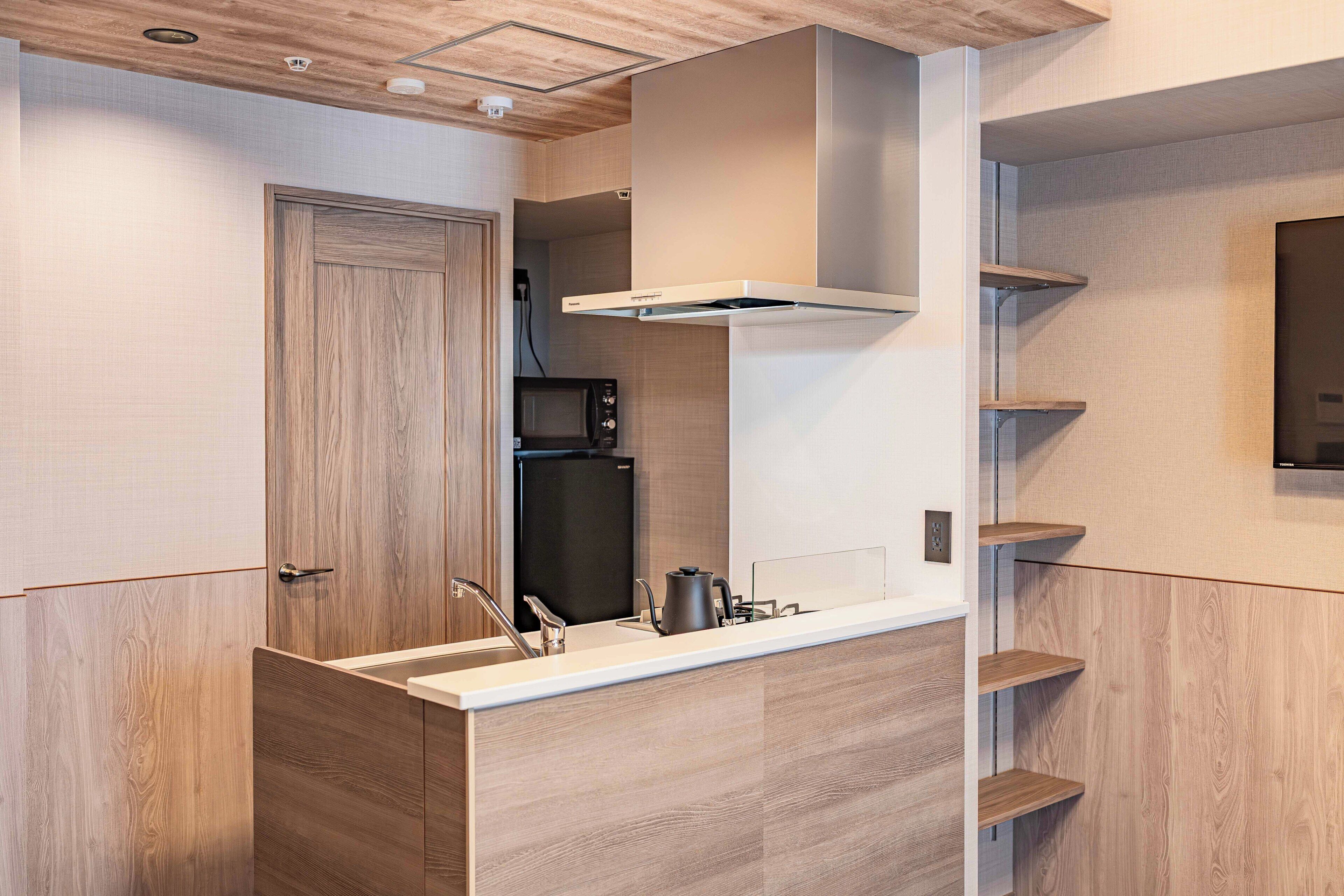 A modern kitchen with a built-in microwave, refrigerator, and stainless steel sink.