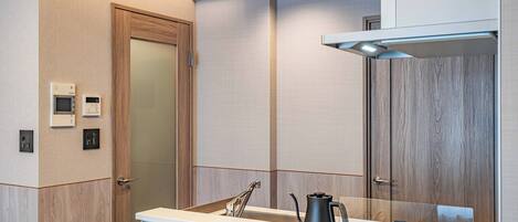 A modern bathroom with a wooden door, a white countertop, and a mirror.