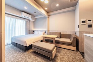 Une chambre d’hôtel moderne équipée d’un lit, d’un canapé, d’une petite table et d’un bureau.