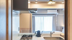 A modern kitchenette with a gas stove, kettle, and sink. - Apartment Hotel 11 Dotonbori 9 (Osaka-shi)