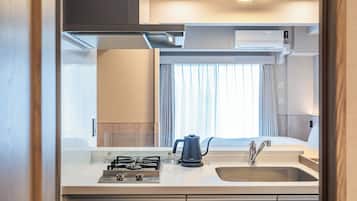 Una kitchenette moderna con estufa a gas, hervidor y pileta.